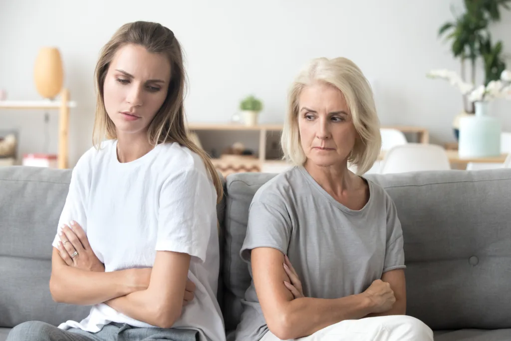 Upset older mother in law and adult daughter sit back to back not talking after fight disagreement, two stubborn old young women ignoring avoiding each other sad by argument, family conflict concept