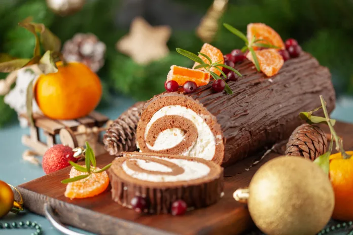 Yule log roll cake with chocolate ganache  on Christmas decorated background