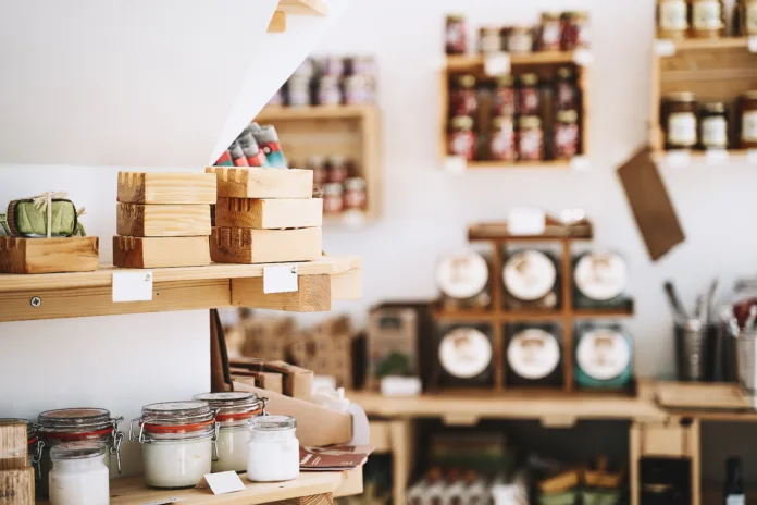 Zero waste shop interior details. Wooden shelves with different food goods and personal hygiene or cosmetics products in plastic free grocery store. Eco-friendly shopping at local small businesses