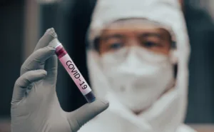 COVID-19 named by WHO for Novel coronavirus NCP concept. Doctor or lab technician in PPE suit holding blood sample with novel (new) coronavirus in Wuhan, Hubei Province, China, medical and healthcare