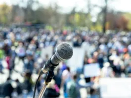 Protest or public demonstration, focus on microphone, blurred crowd of people in the background